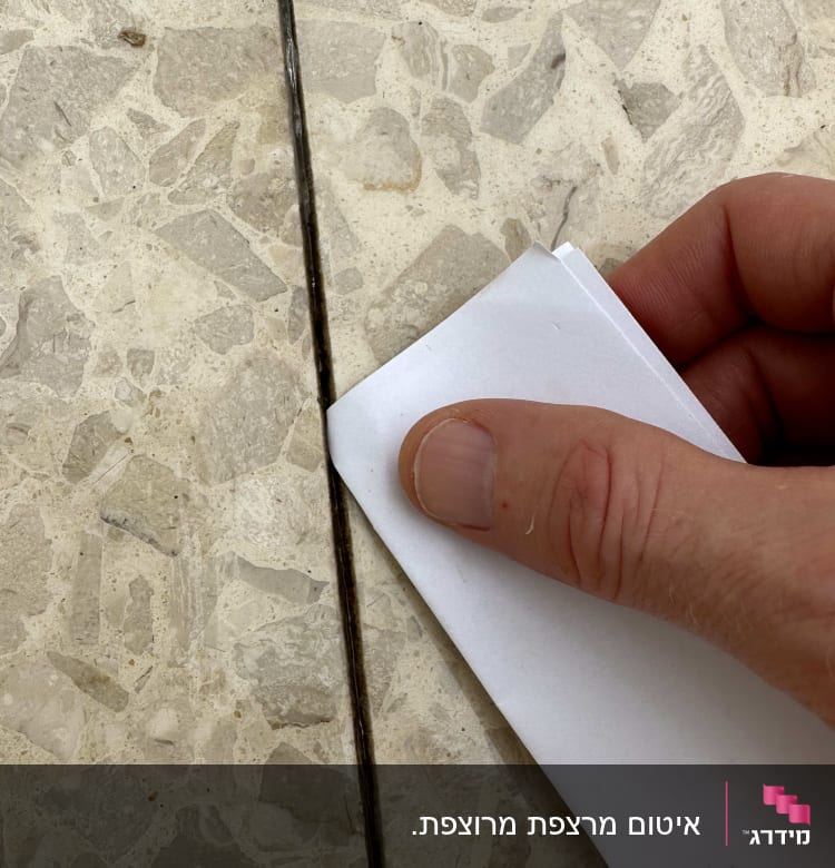 יד מחזיקה נייר על חריץ ברצפה